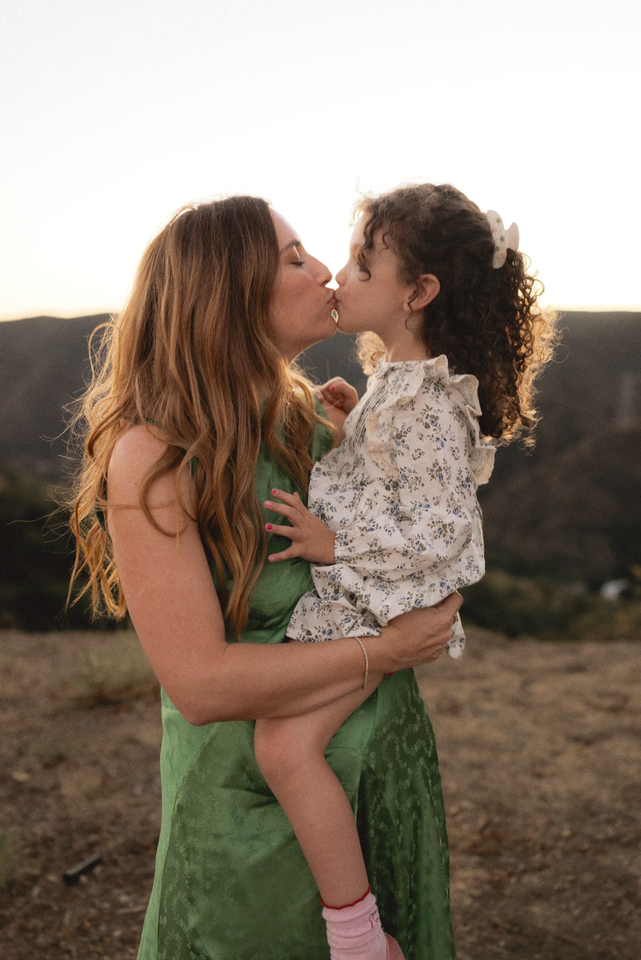 Mother kissing her young daughter during a family session